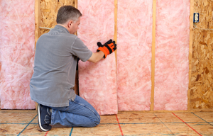 Pink fiberglass batt insulation being installed in a wall