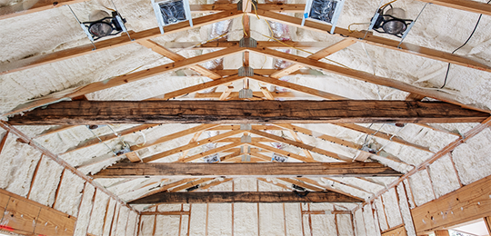 Interior photo of home mid-construction, with spray foam insulation applied in the ceiling and walls