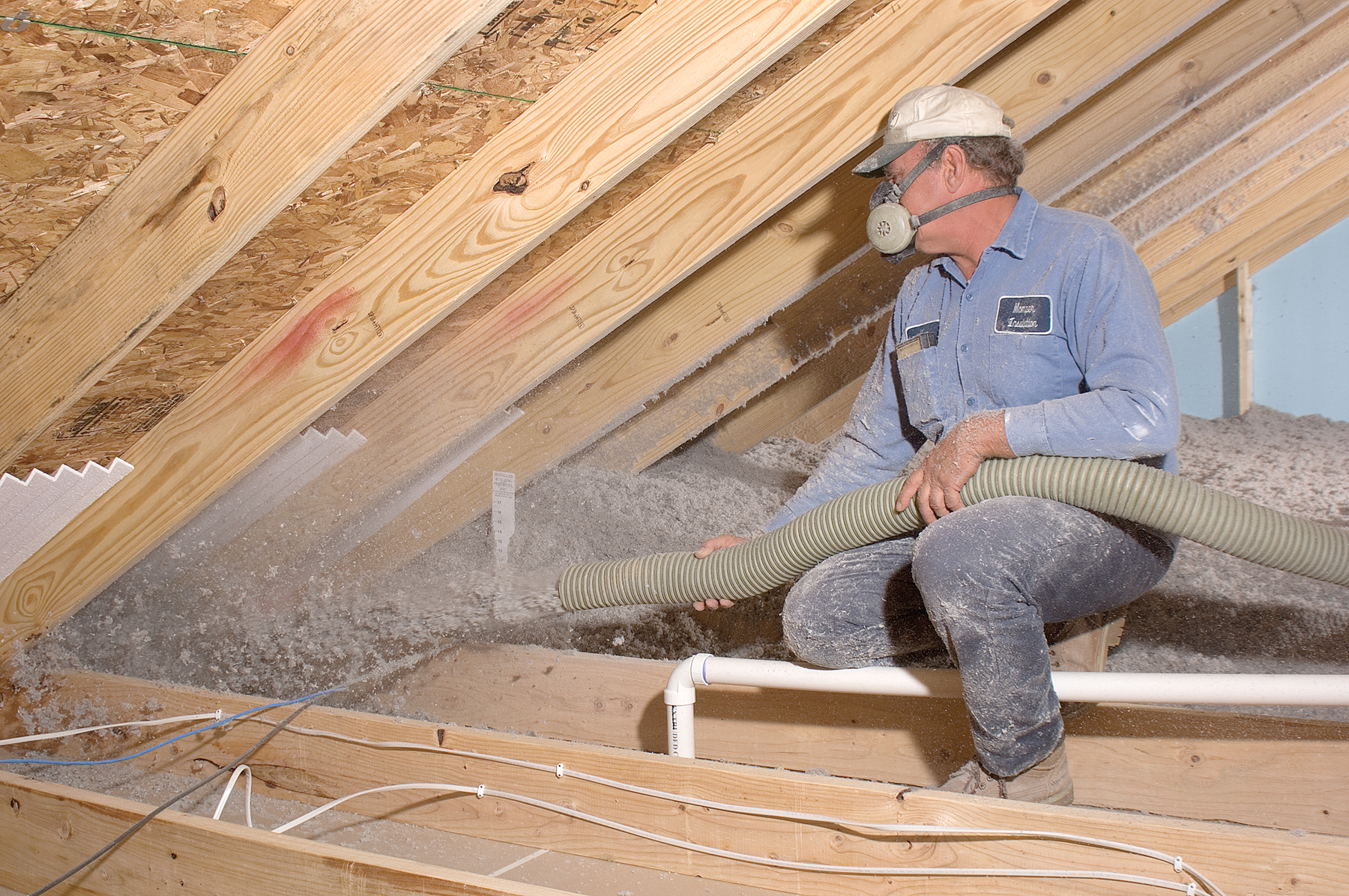 Technician installing Owens Corning blown-in attic insulation.
